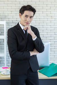 Portrait of young man standing against wall