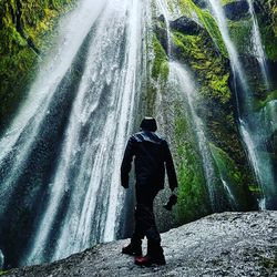 Rear view of man looking at waterfall