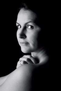 Portrait of young woman against black background