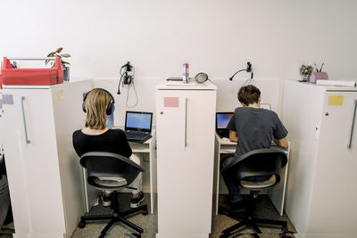 Rear view of male and female high school students studying while sitting on chairs in library