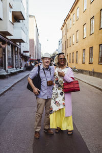 Active senior couples with arms around standing on street in city