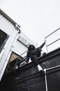 Low angle view of man working on building against clear sky