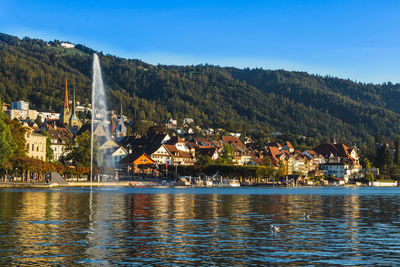 Scenic view of lake zug by buildings against sky