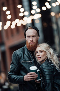 Portrait of young couple holding camera outdoors