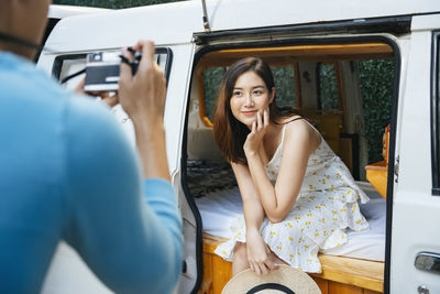 Young man photographing woman sitting in motor home