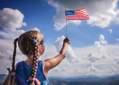 Patriot and national flag day celebration. little patriot sitting on the meadow and holding usa flag