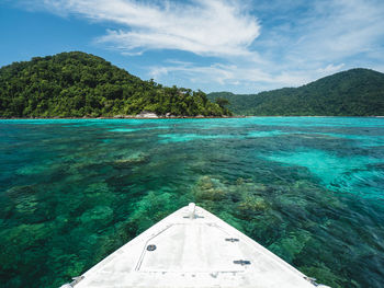 Surin island snorkeling spot clear turquoise sea and coral reef with boat prow foreground. thailand.