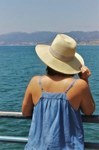 Rear view of woman standing by sea