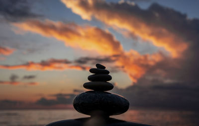 Stack of stones against sky during sunset