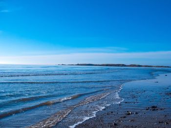 Scenic view of beach against blue sky