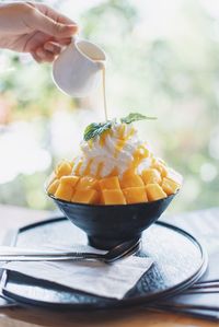 Cropped hand pouring milk on fruit slice