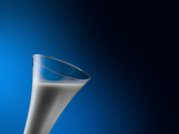 Low angle view of glass against blue background