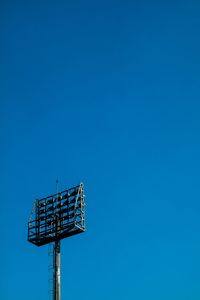 Low angle view of crane against clear blue sky
