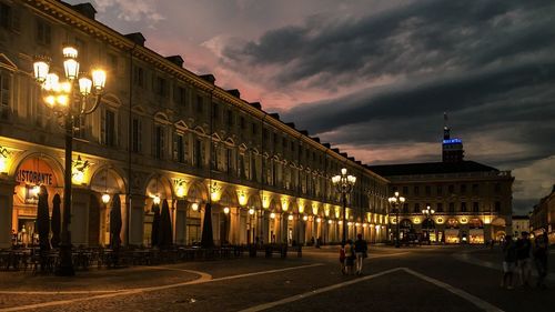 People on city street against cloudy sky