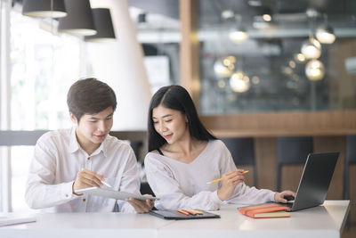 Young woman using phone while sitting on table