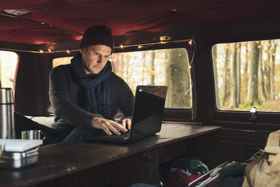 Male freelancer working on laptop in camping van