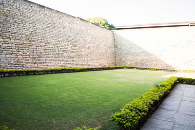 Built structure on lawn by wall against sky