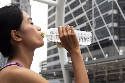 Young woman wearing tank top drinking water