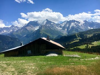 Built structure on field by mountains against sky