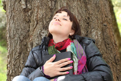 Low section of woman sitting on tree trunk