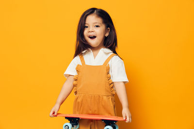 Portrait of young woman standing against yellow background