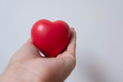 Close-up of hand holding heart shape over white background