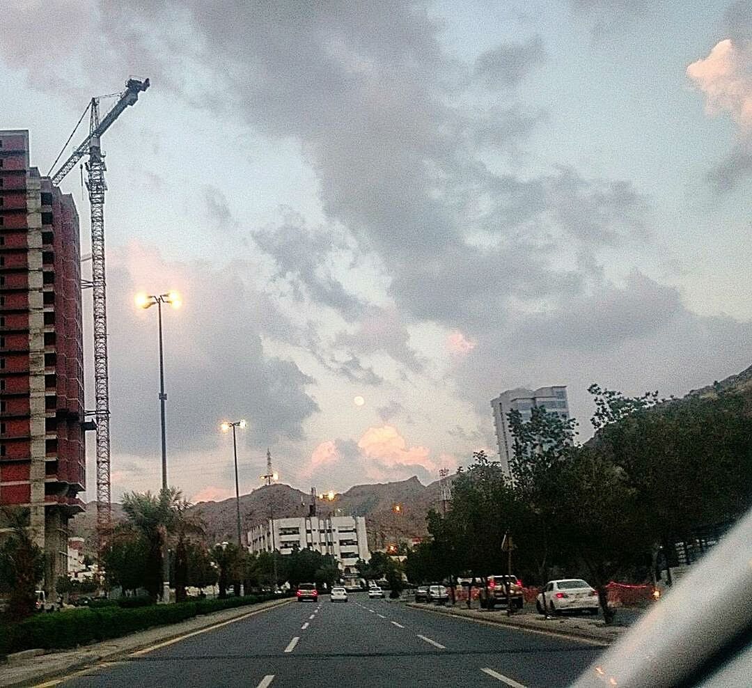 building exterior, architecture, built structure, sky, transportation, street, road, city, the way forward, cloud - sky, car, street light, land vehicle, cloudy, mode of transport, road marking, diminishing perspective, building, cloud, tree