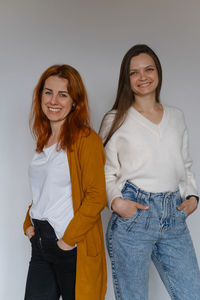 Happy two women in their 20s 40s over white wall. employees in casual outfit looking at the camera