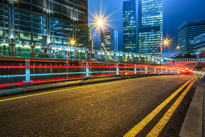 Light trails on road against buildings at night