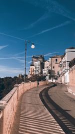 Street amidst buildings against blue sky