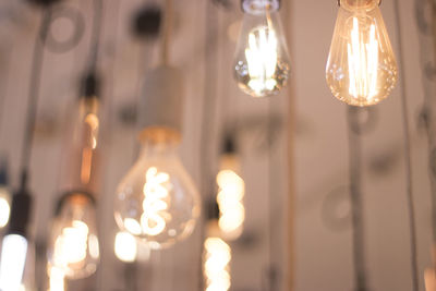 Close-up of illuminated light bulbs hanging from ceiling