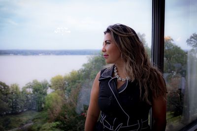 Woman looking at lake through window