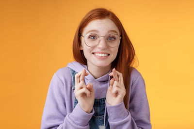 Portrait of smiling young woman against yellow background