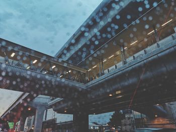 Low angle view of illuminated bridge and buildings against sky