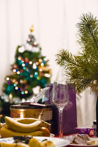 Close-up of wine glass with food on table against decorated christmas tree