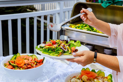 Midsection of woman serving food in plate while standing at party