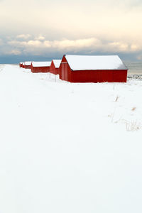 Lifeguard hut on snow covered land against sky