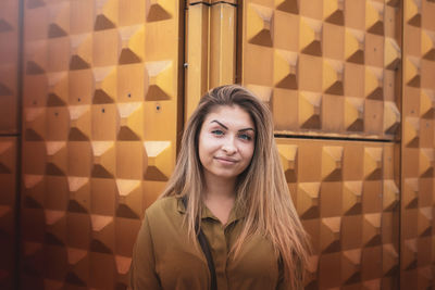 Portrait of smiling young woman standing against brick wall