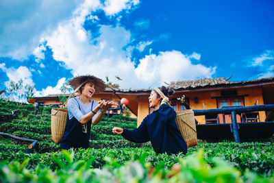 Men sitting on field against sky