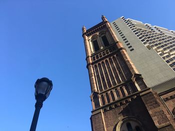 Low angle view of street and buildings against clear blue sky