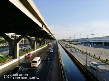 Vehicles on highway in city against sky