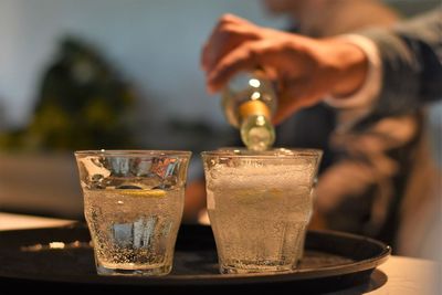 Close-up of hand pouring wine in glass on table