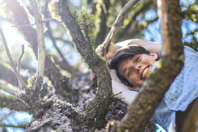 Portrait of young woman standing on tree in forest