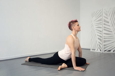 Young woman with red hair is doing gymnastics on a yoga mat or pilates mat.