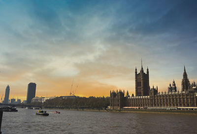 View of river and buildings against sky during sunset