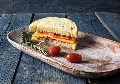 High angle view of ham sandwich with tomatoes and rosemary in tray