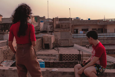 Friends on terrace against sky during sunset