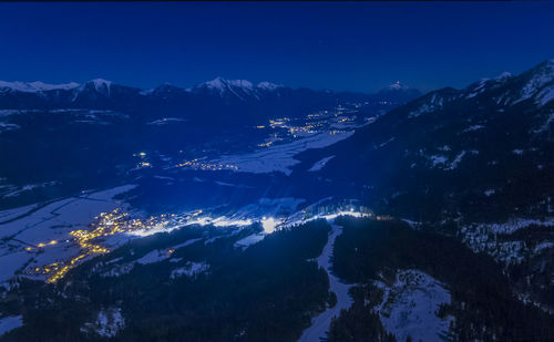 Aerial view of illuminated mountains against blue sky at night