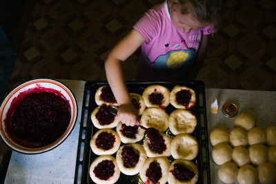 A girl prepares pies with lingonberries in the kitchen