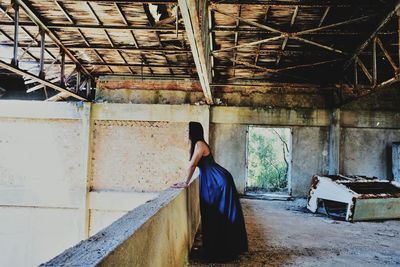 Rear view of woman sitting in abandoned building